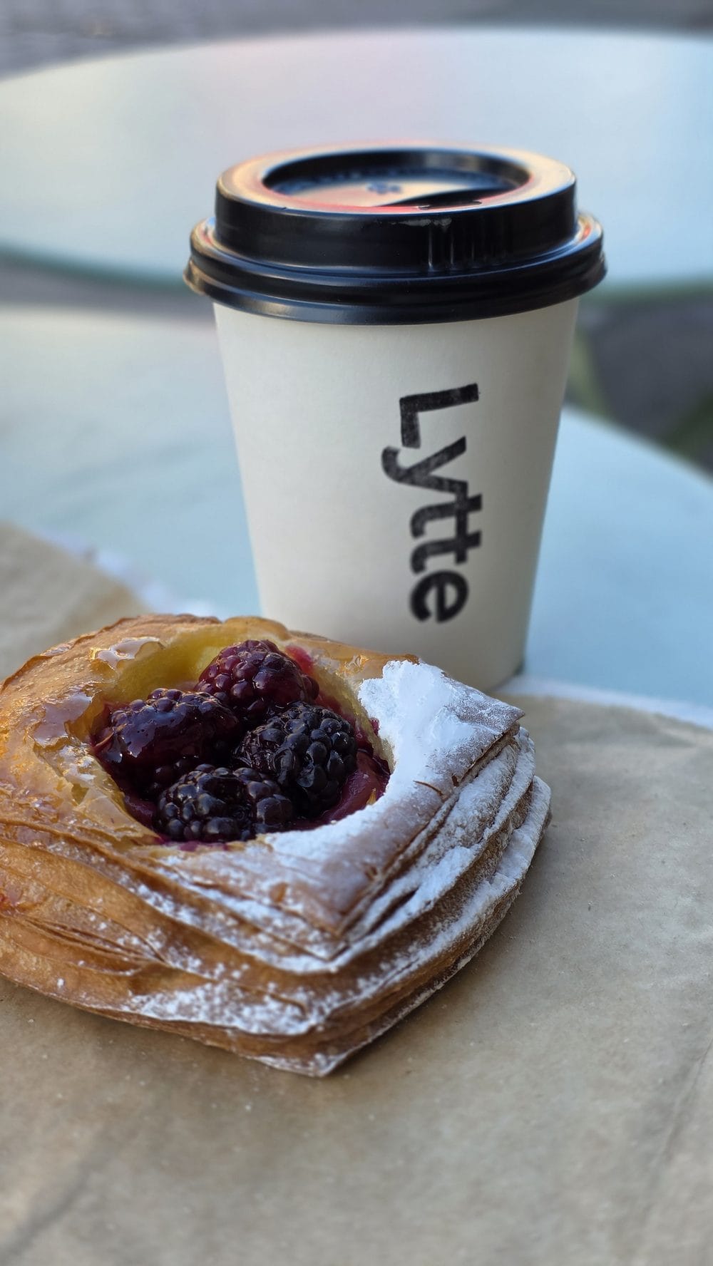 A Lytte takeaway cup beside a berry custard danish