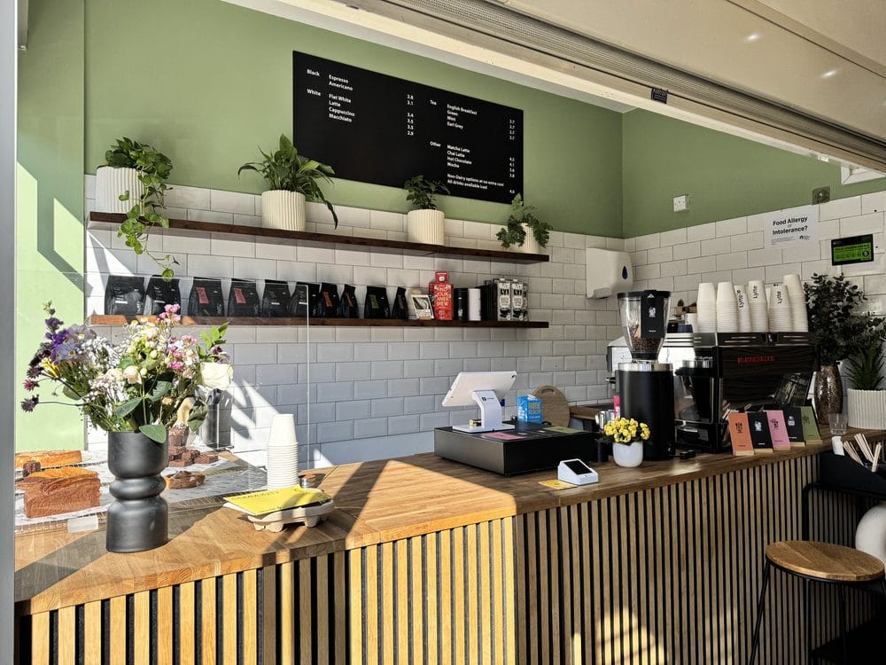 Inside Lytte Coffee — wooden slatted counter, sage green wall and the menu board