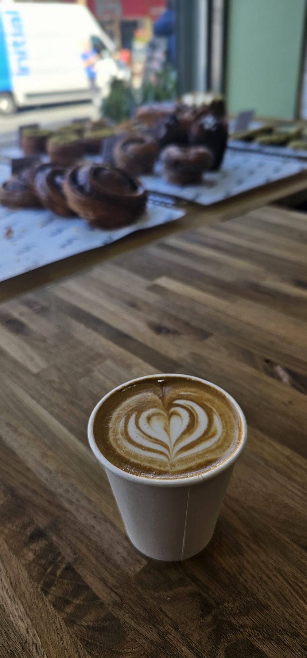 A flat white with latte art on the wooden counter at Lytte